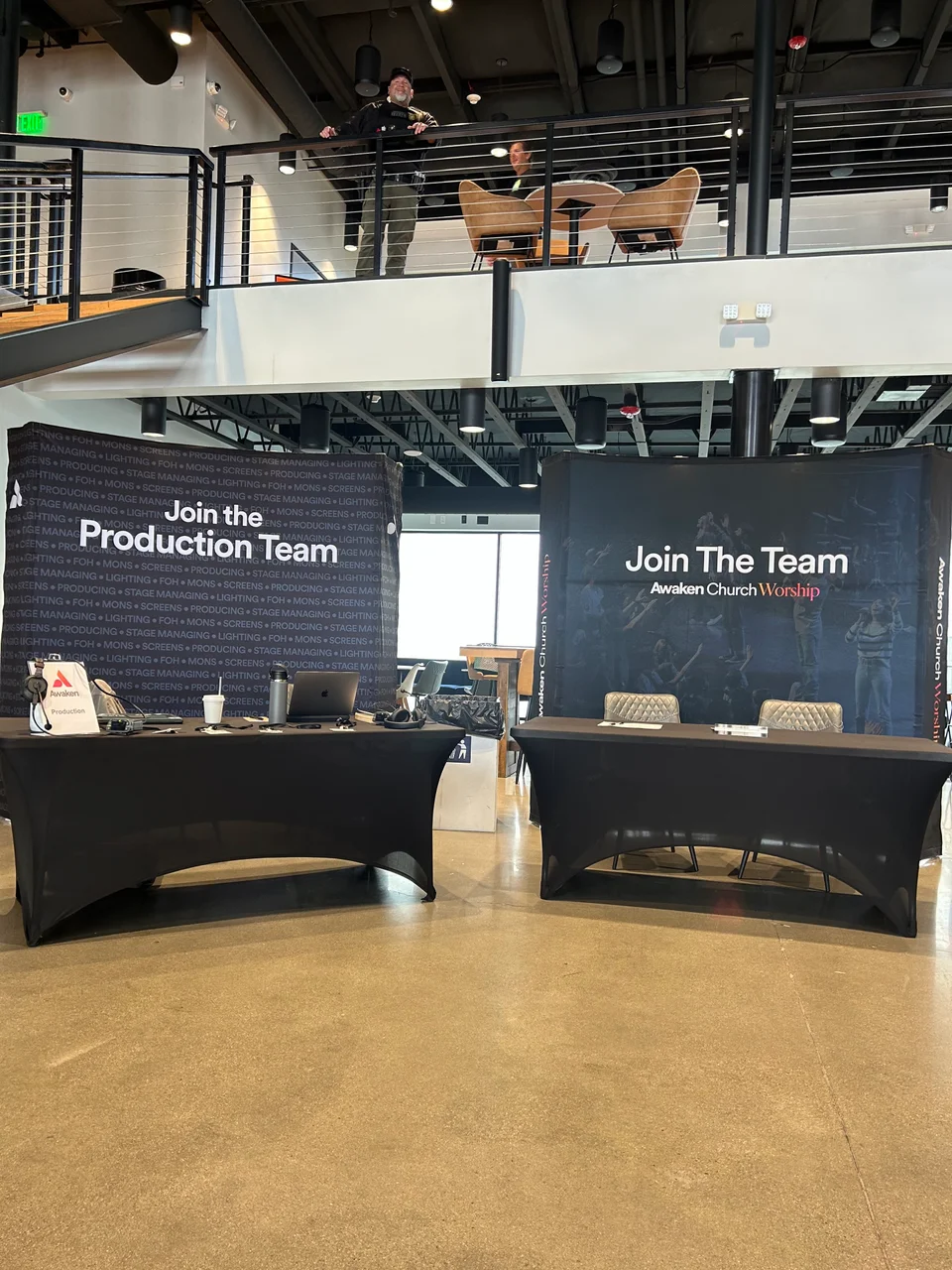 Tables and signs for worship and production teams in a church lobby.
