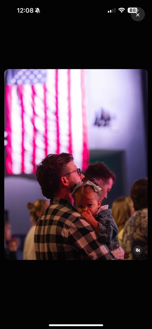 Tim holding a young child among the congregation during a church service.